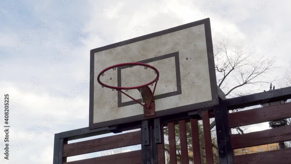 Old basketball hoop in a street park against the background of the sky and the silhouette of a tree Old basketball hoop in a street park against the background of the sky and the silhouette of a tree