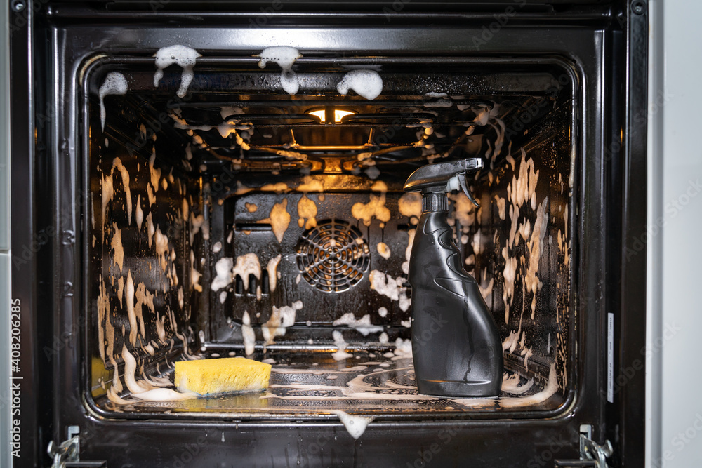 the spray bottle and sponge in the middle of the oven is covered with  cleaning foam. home cleaning concept Stock Photo | Adobe Stock