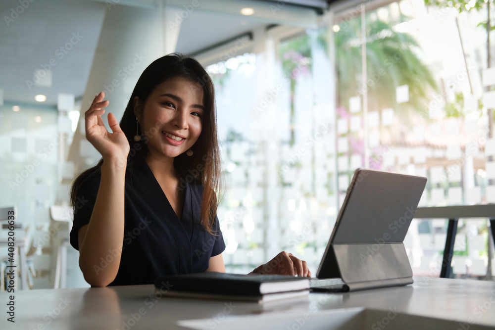 Portrait of happy young woman working on tablet pc while sitting at her working place in office. Portrait of happy young woman working on tablet pc while sitting at her working place in office.