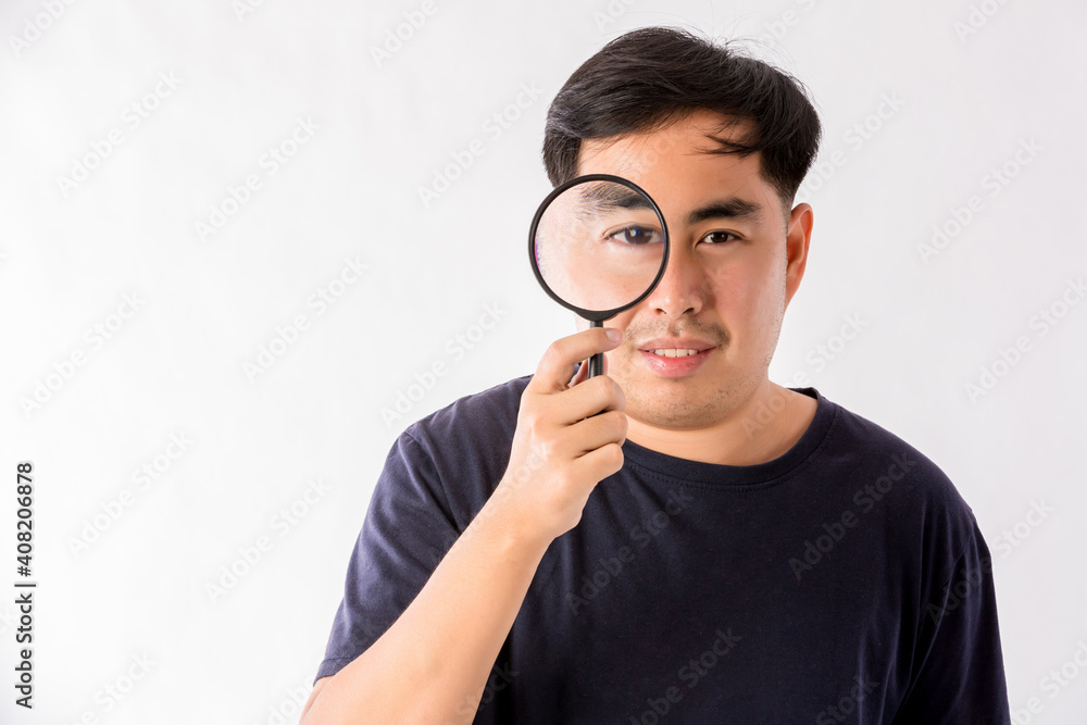 Man holding magnifying glass on white background. man with a magnifying glass in studio. Positive curious man in casual wear looking at through magnifier Man holding magnifying glass on white background. man with a magnifying glass in studio. Positive curious man in casual wear looking at through magnifier