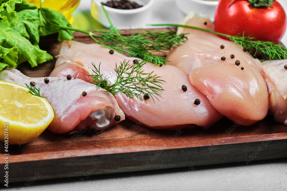 Raw chicken fillet and legs on wooden plate with fresh vegetables. Close up Raw chicken fillet and legs on wooden plate with fresh vegetables. Close up