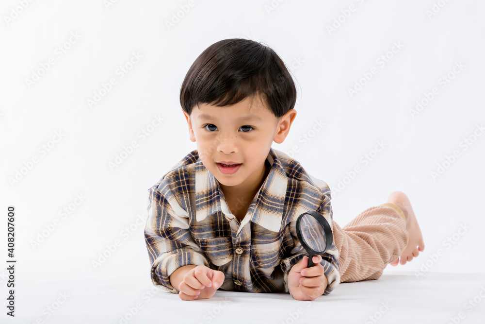 Child holding magnifying glass on white background. Boy with a magnifying glass in studio. Child holding magnifying glass on white background. Boy with a magnifying glass in studio.