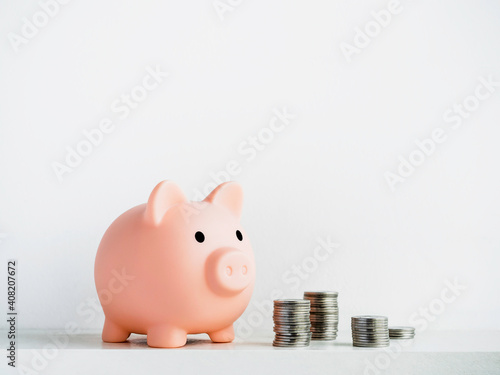 Cute piggy bank, pink color with stacks of coins isolated on white background