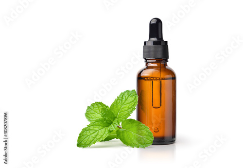 Peppermint essential oil in amber dropper bottle with fresh mint leaf isolated on white background.