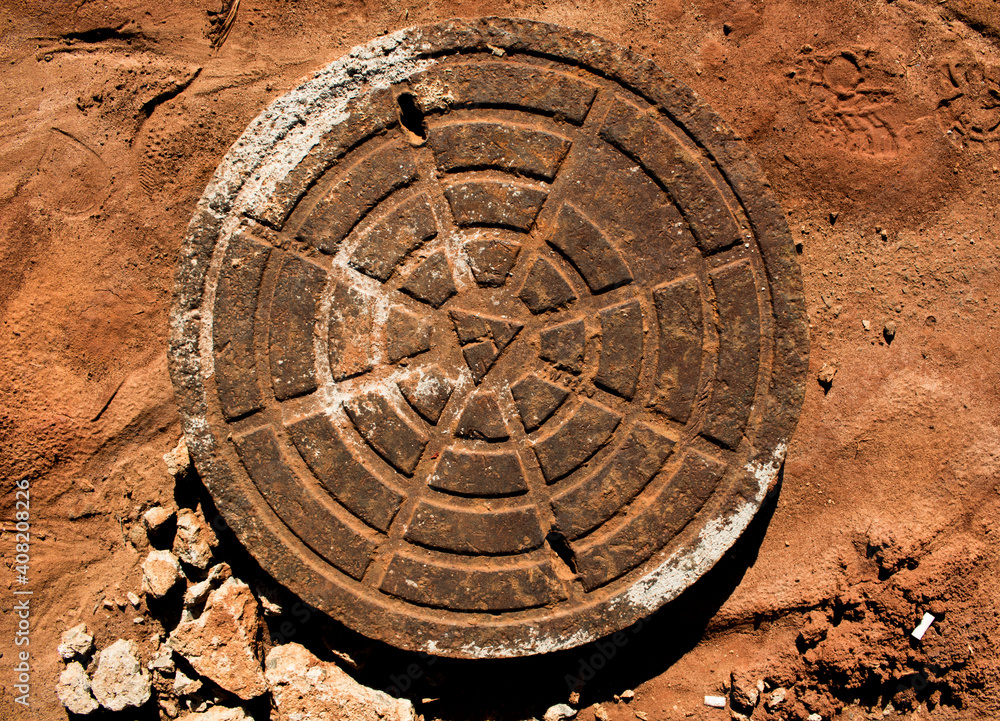 Old and rustic manhole cover placed over ground
