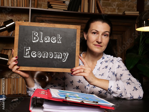 Woman's hand showing chalkboard with phrase Black Economy - closeup shot on grey background