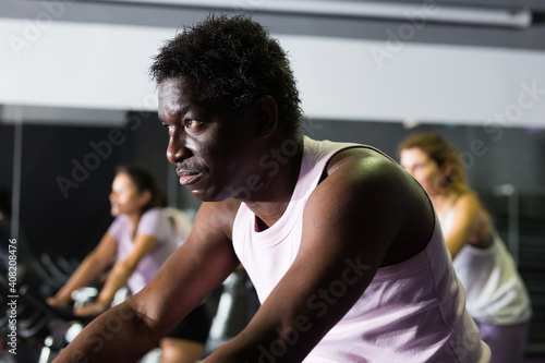 African american man ride stationary bike in a fitness club. High quality photo