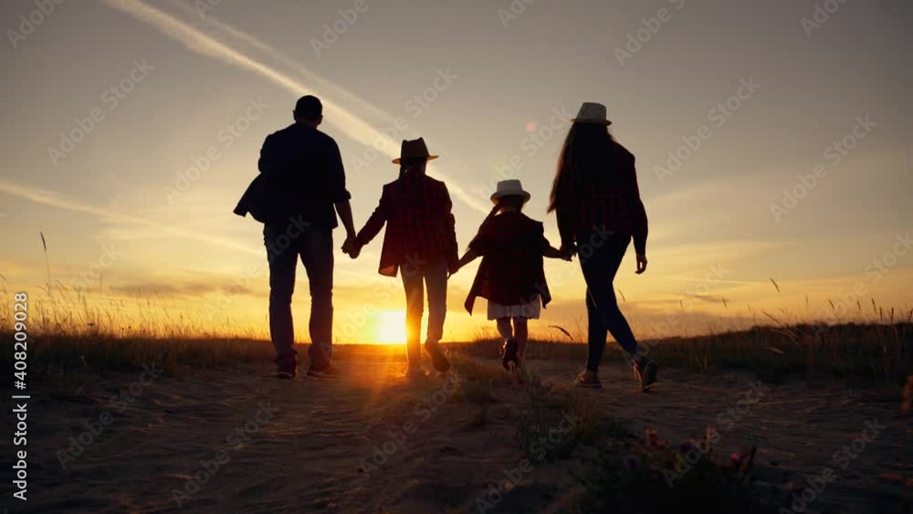 Young happy family in park at sunset. Silhouette of family in park. Happy family hiking. Silhouette of group of people in field at sunset. Happy family concept. Parents and children hiking in park. Young happy family in park at sunset. Silhouette of family in park. Happy family hiking. Silhouette of group of people in field at sunset. Happy family concept. Parents and children hiking in park.