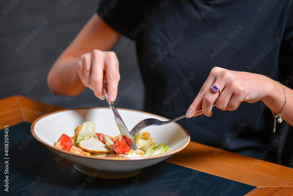 Young woman eats caesar salad of traditional recipe in restaurant or diner. Eating out concept.