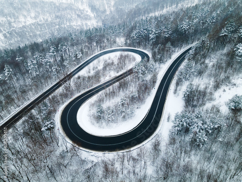 Curvy Windy Road in Snow Covered Forest, Top Down Aerial Drone View. © marcin jucha
