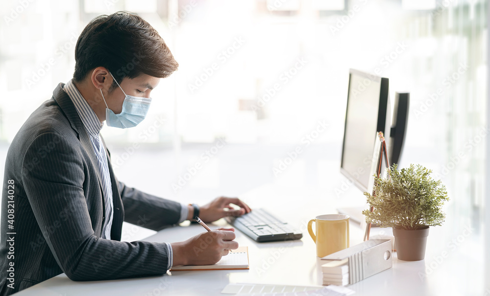 oung asian businessman with protective mask working on document.