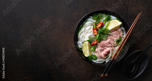 Pho Bo vietnamese soup with beef and rice noodles on a dark background, top view, copy space