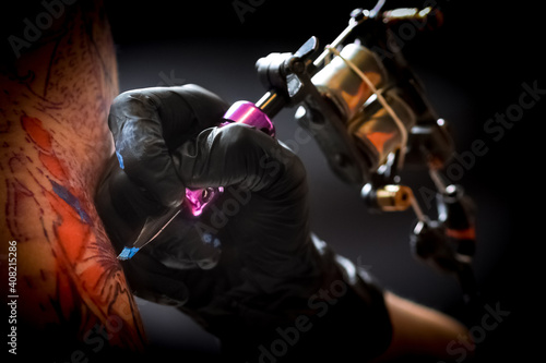 Female tattoo artist making tattoo on a men’s arm