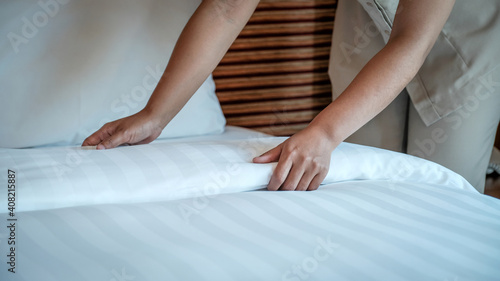 Hands of hotel maid making the bed in the luxury hotel room ready for tourist travel