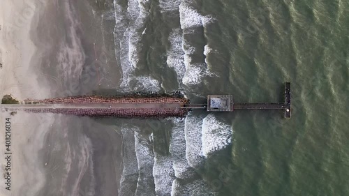 Spectacular aerial shot of a long walkway coming to an end at the dock. Waves breaking around the jetty. photo