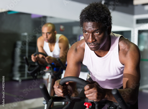 Young adult man doing cardio workout cycling bike at fitness center