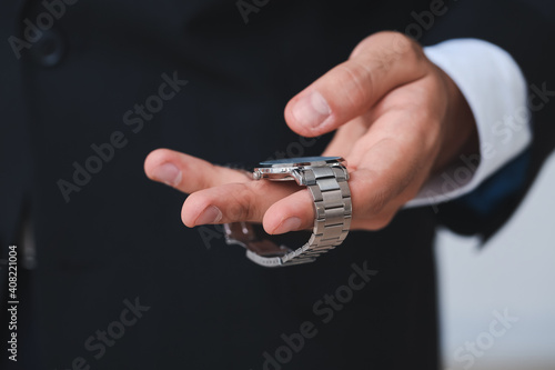 Young businessman holding stylish wristwatch, closeup