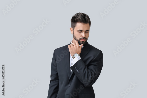 Handsome businessman with stylish wristwatch on light background