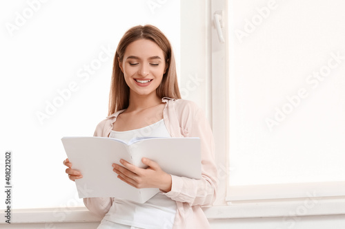Beautiful woman reading blank magazine in room