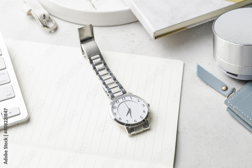 Stylish wristwatch and notebook on light background Stylish wristwatch and notebook on light background