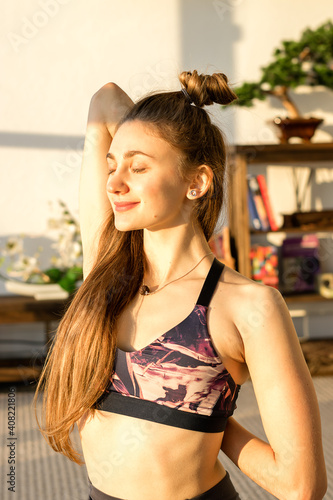 Slika na platnu Young attractive woman practicing yoga and stretching of the shoulder joints and pectoral muscles indoors