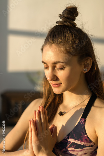 Young attractive woman practicing yoga and doing namaste mudra gesture. Yoga training concept.Healthy lifestyle.Slow living concept.