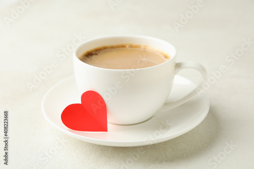 Cup of coffee with red heart on white textured table