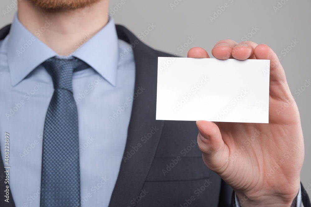 Businessman ,Business Man's hand hold showing business card - close up shot on grey background. Show a blank piece of paper. Paper visit card Businessman ,Business Man's hand hold showing business card - close up shot on grey background. Show a blank piece of paper. Paper visit card
