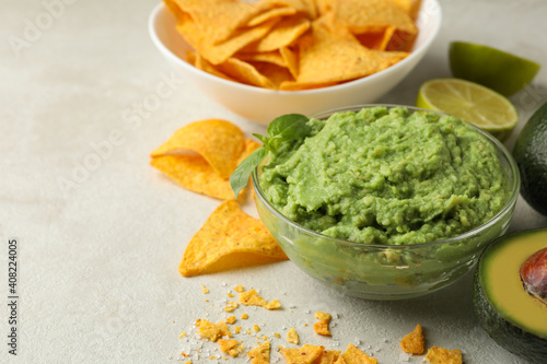 Concept of tasty eating with guacamole and chips on white textured background, space for text