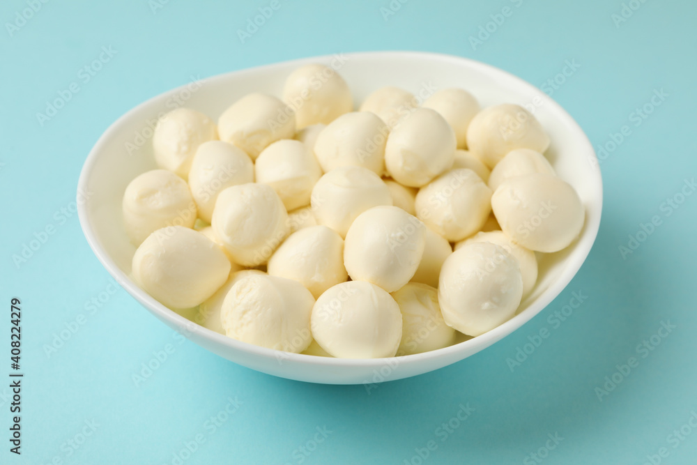 Bowl with fresh mozzarella cheese on blue background Bowl with fresh mozzarella cheese on blue background