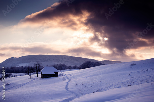 Small cottage in magic sunset in winter mountains