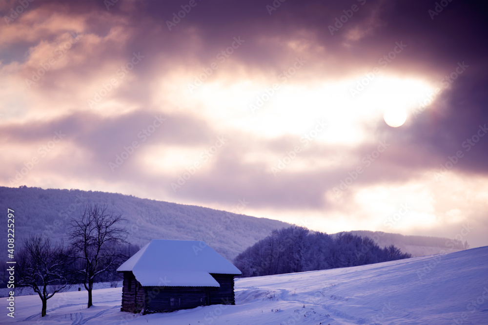 Small cottage in magic sunset in winter mountains