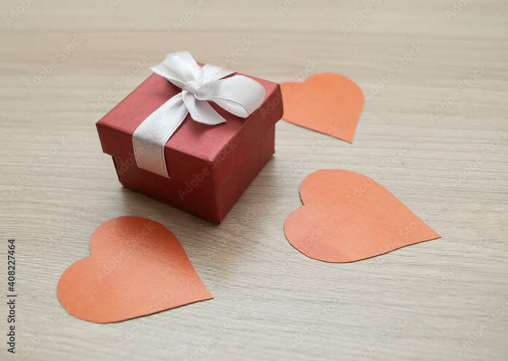 gift box with a bow and a hearts made of paper on a light wooden background gift box with a bow and a hearts made of paper on a light wooden background