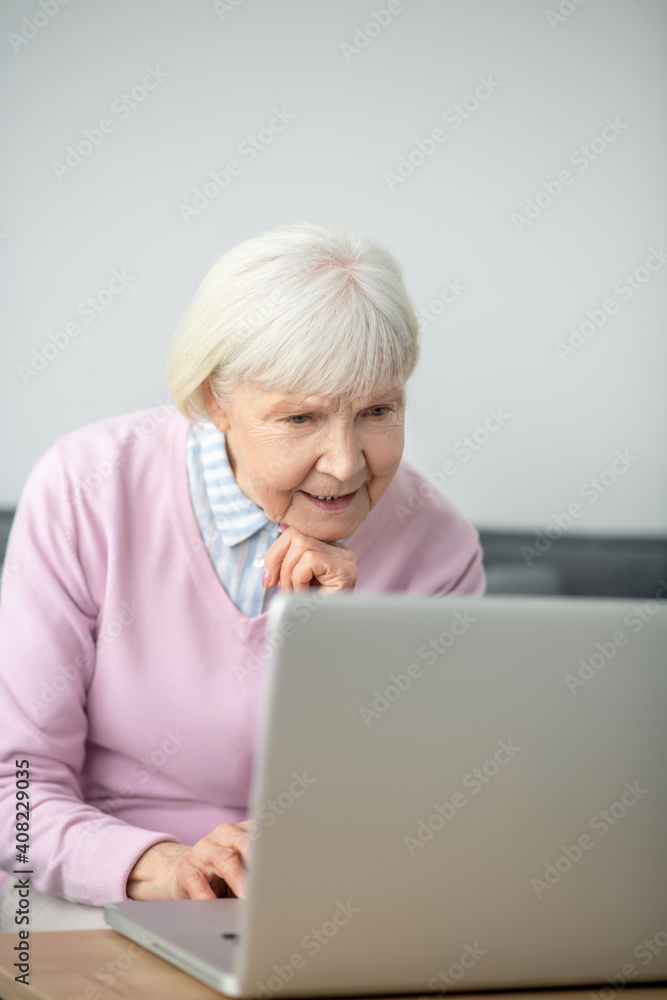 Senior woman sitting in front of laptop and looking involved Senior woman sitting in front of laptop and looking involved