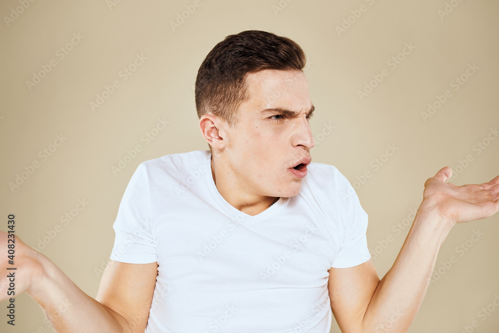 Emotional man facial expression gesture with hands white t-shirt beige background Emotional man facial expression gesture with hands white t-shirt beige background