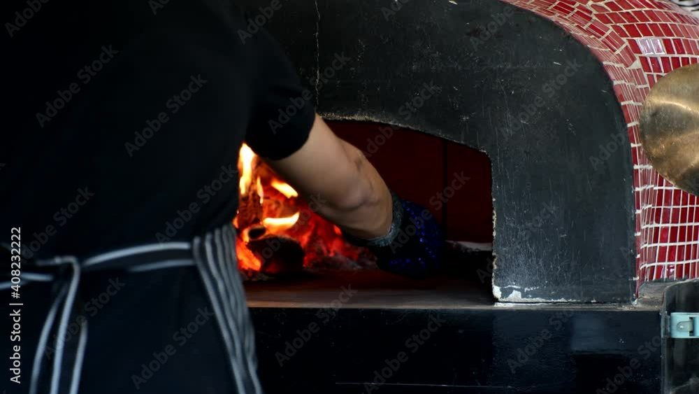 Chef is Placing Pizza in Wood fired Pizza Oven. Traditional Italian Food. Chef is Placing Pizza in Wood fired Pizza Oven. Traditional Italian Food.