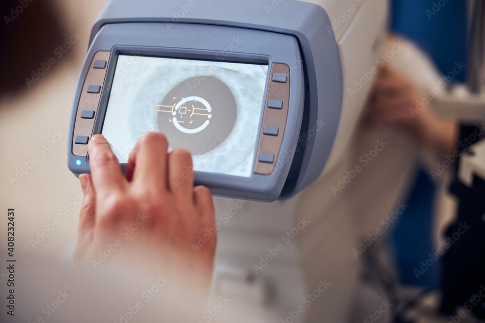 Experienced doctor using machine while checking eyesight of patient in office of pediatric ophthalmology Experienced doctor using machine while checking eyesight of patient in office of pediatric ophthalmology