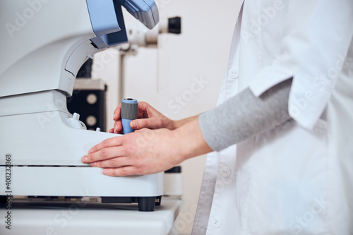 Focused image of experienced doctor looking lens in patient eyes with special machine