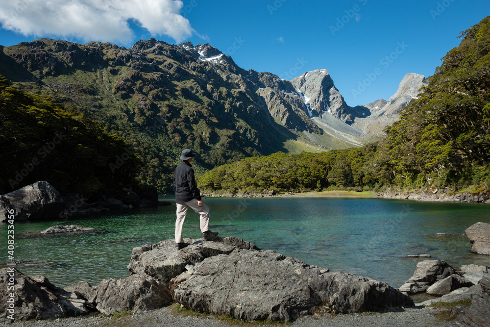 A man standing on the rocks and enjoying the views of Lake Mackenzie at Routeburn Track, South Island, New Zealand