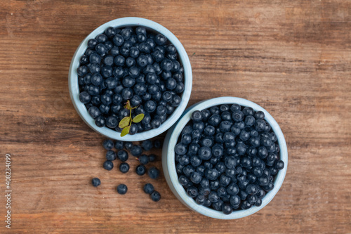 Blueberries in blue bowls on wooden board background. Healthy eating top view