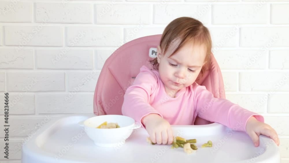 Little baby girl eating and playing with vegetables. Top view Little baby girl eating and playing with vegetables. Top view