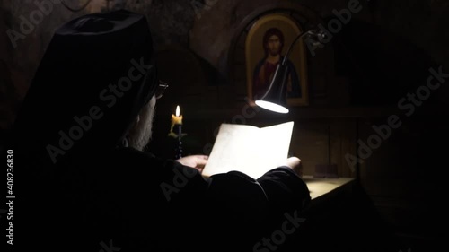 The holy father reads a book by candlelight.