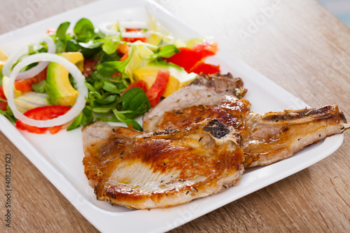 Fried pork escalope with salad from avocado  tomatoes and corn salad