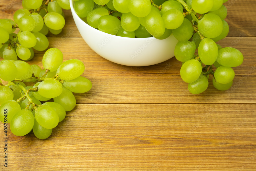 Green grapes in white ceramic bowl on wooden table with empty space. Green grapes in white ceramic bowl on wooden table with empty space.
