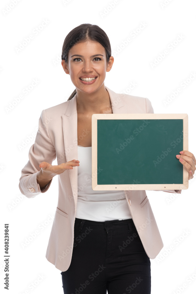 happy brunette woman in pink jacket showing blackboard and smiling happy brunette woman in pink jacket showing blackboard and smiling