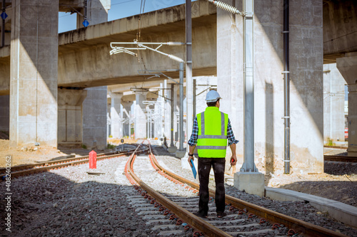 Portrait engineer under inspection and checking construction process railway and checking work on railroad station .Engineer wearing safety uniform and safety helmet in work.