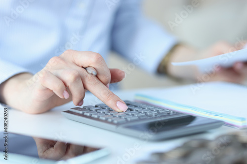 Female hand holds pen and presses numbers on calculator