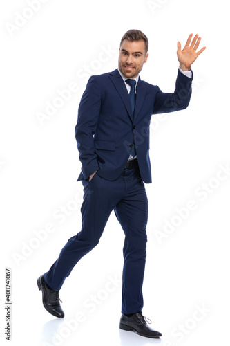 full body picture of happy businessman holding hand up and waving