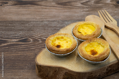 close up Egg tart dessert snack bakery with wooden spoon and fork on wooden plate. cafe menu with copy space for text.