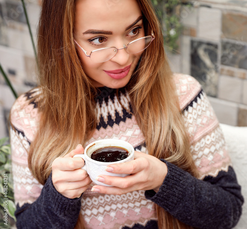 A woman with glasses for vision drinks coffee.